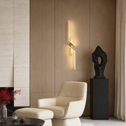 Modern geometric wall sconce with gold finish, illuminating a cozy living room corner.