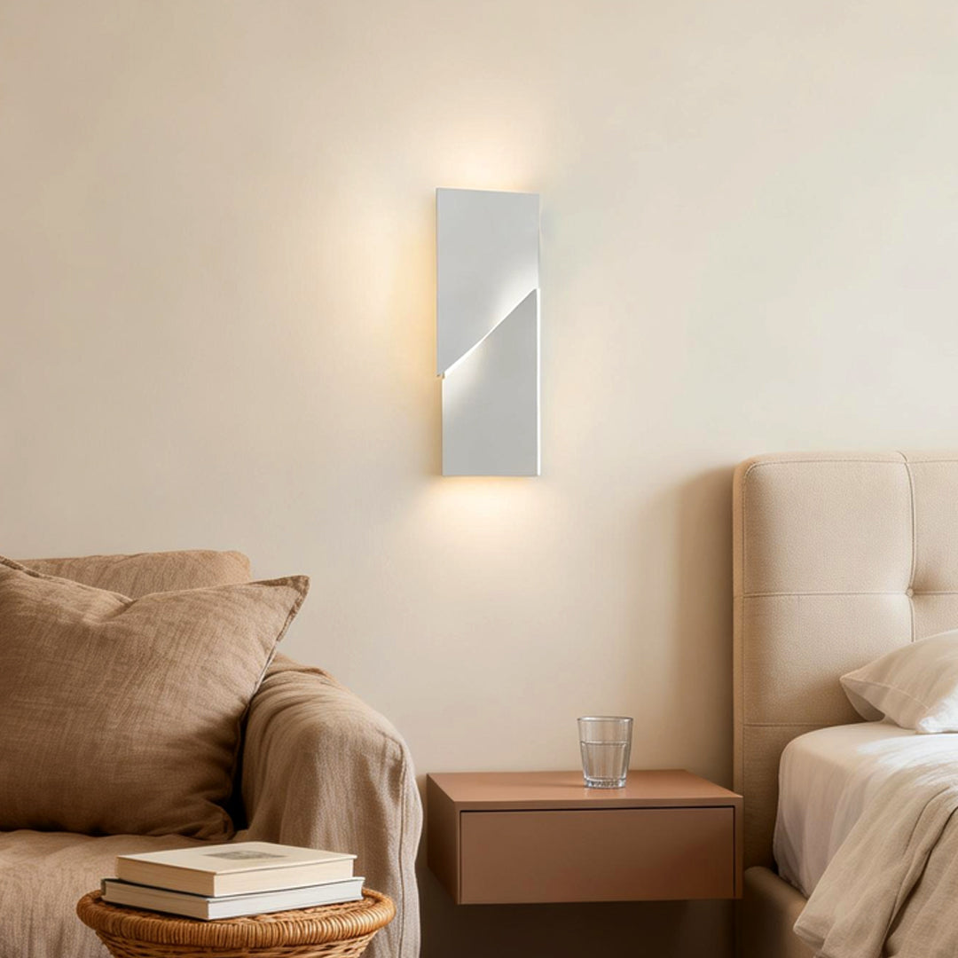 Geometric wall sconce light illuminating a modern bedroom with elegant angular glow.