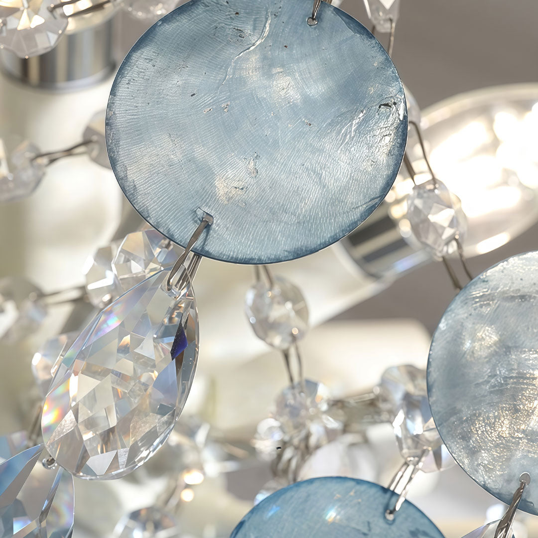 Close-up of glam chandelier showing textured blue glass discs and sparkling crystal accents.