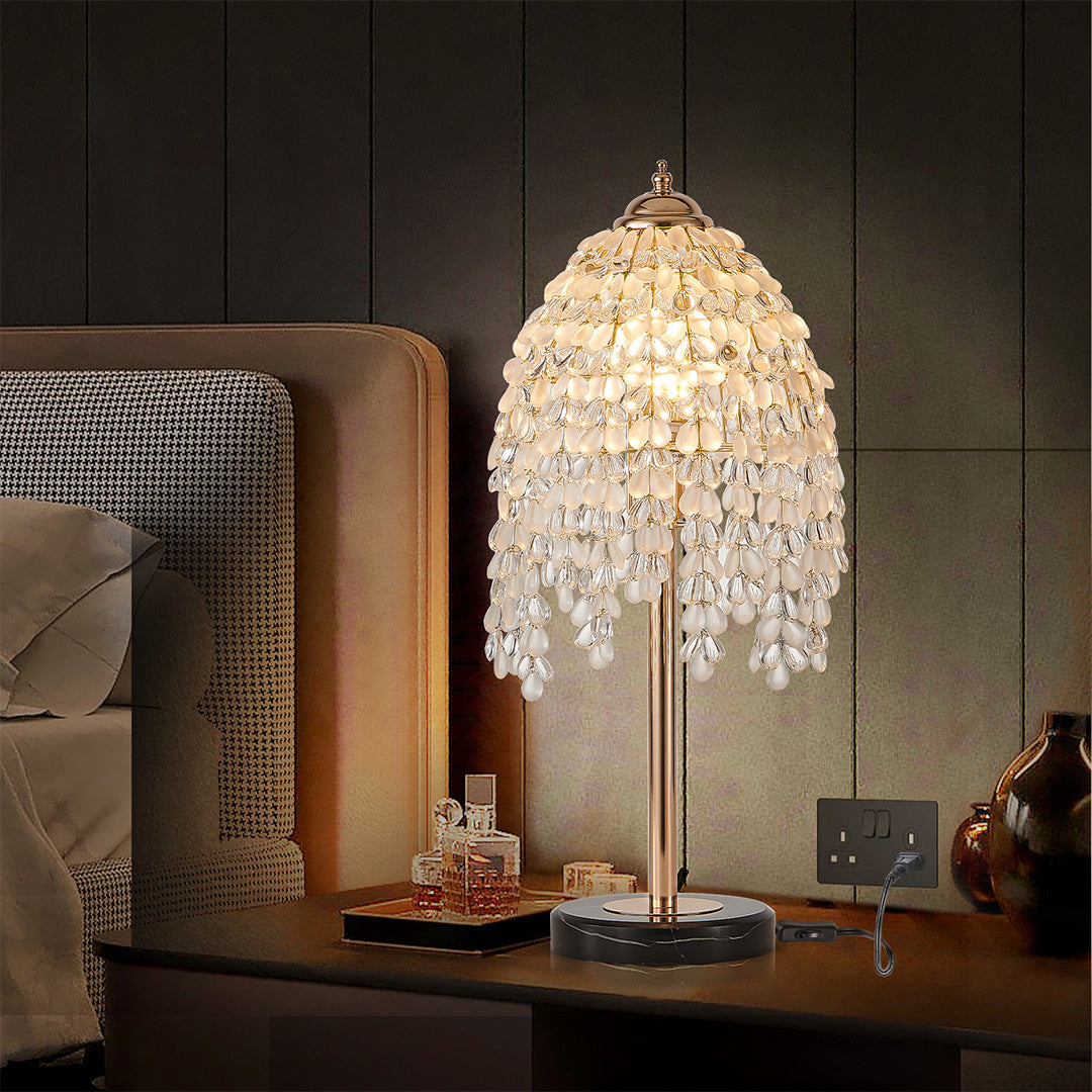 Glamorous gold bedside table lamp with glass shade chandelier styling creating warm ambient glow on contemporary nightstand.