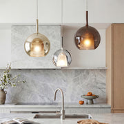 Chic glass ball pendant light set in smoke and gold over a luxury marble kitchen island desk.