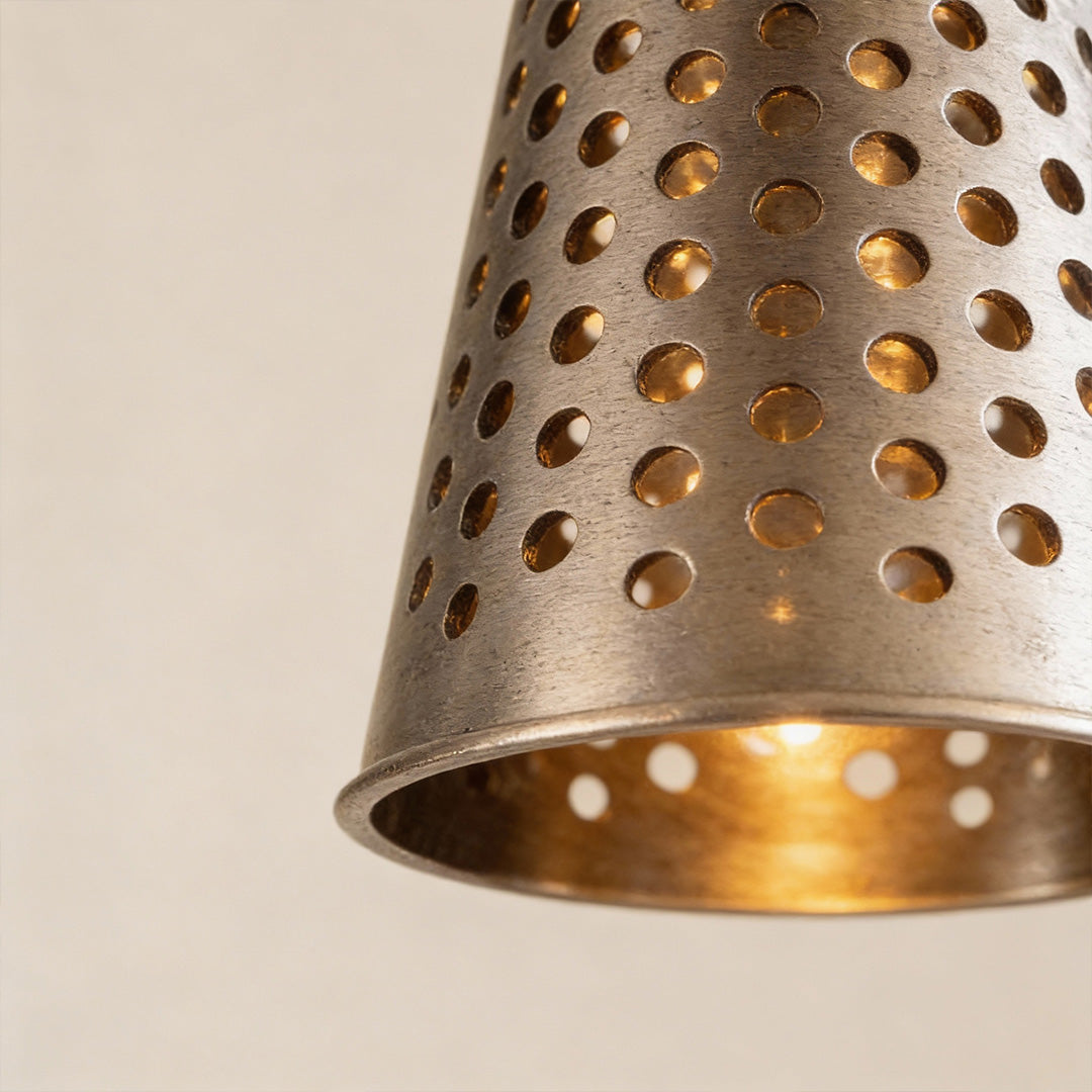 Glass ball pendant lights featuring a perforated metal cone shade with warm inner glow, highlighting refined craftsmanship and modern style.