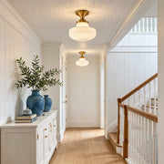 Glass ceiling light fixtures installed in a bright hallway with classic transitional interior styling.