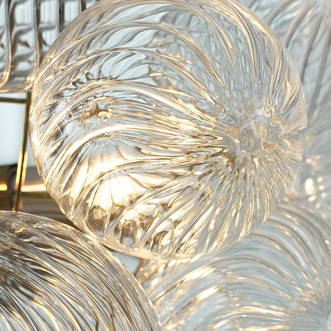 Glass chandelier art close-up showing textured spiral glass discs with illuminated detailing.