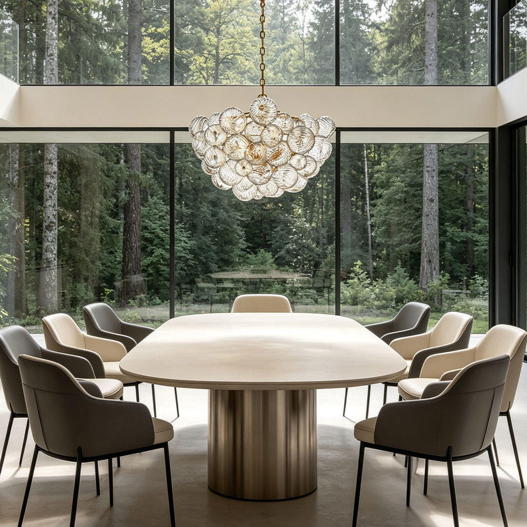 Glass chandelier art hanging above a modern dining table with panoramic forest views.