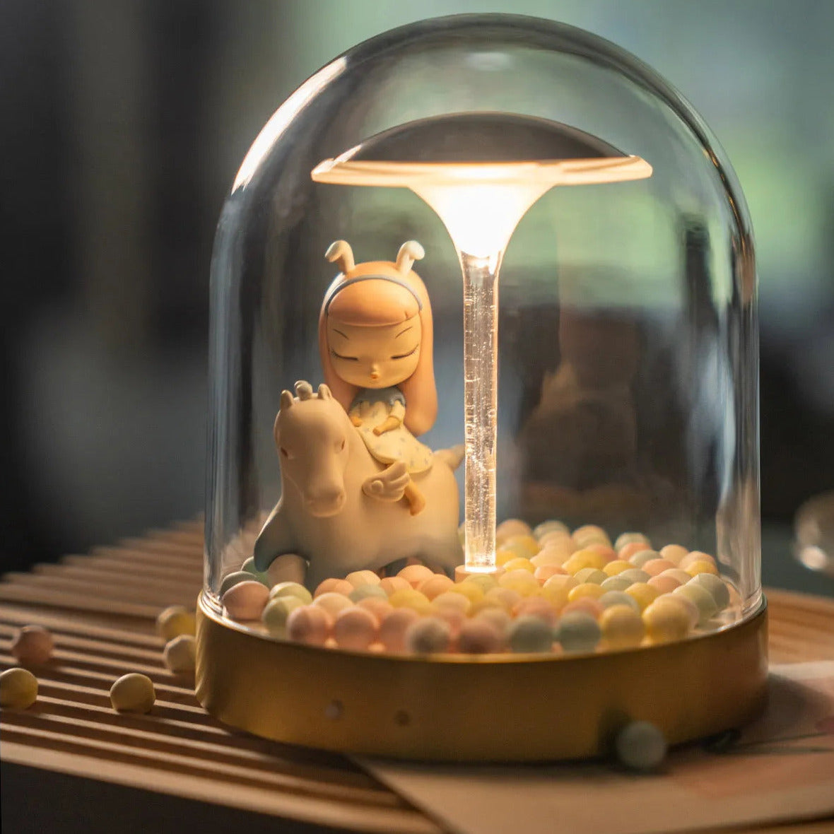 Glass dome LED lights with a decorative figurine inside, glowing softly on a table.