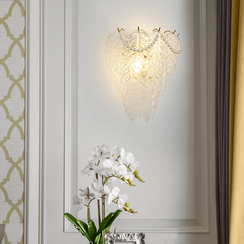Close-up of glass feather wall light showcasing detailed feather patterns and warm illumination.