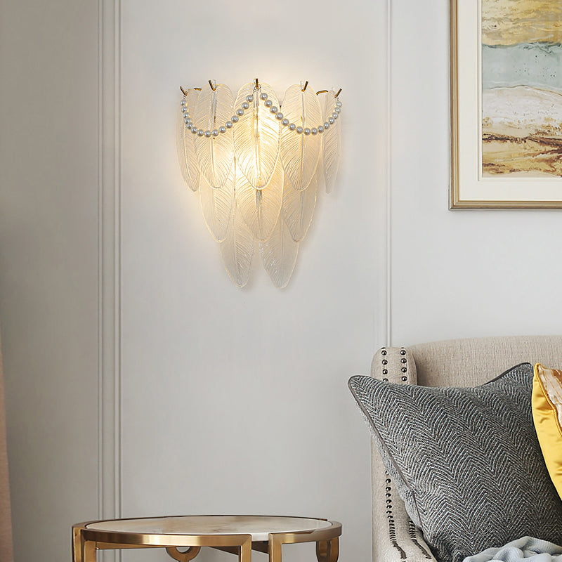 Glass feather wall light with intricate feather-like design in a contemporary bedroom.