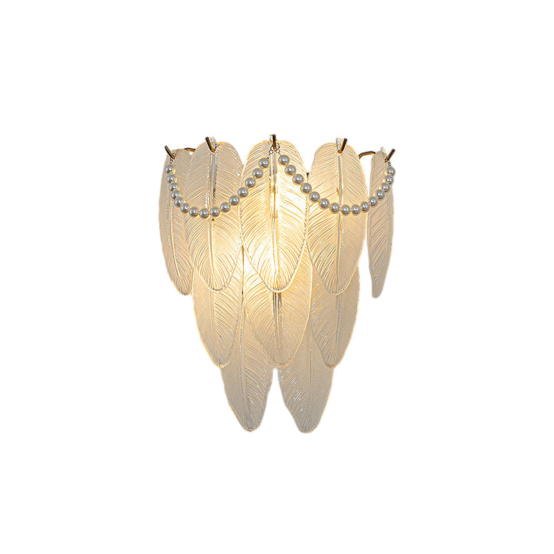 Glass feather wall light with a soft glow, adding elegance to a bedroom setting.