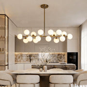 Glass globe linear chandelier illuminating a modern dining area with warm, ambient glow.