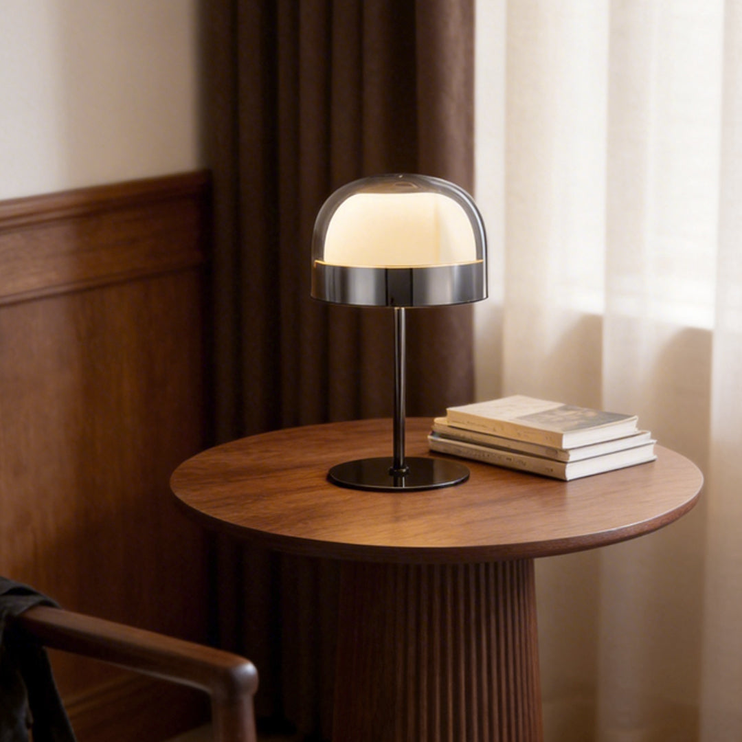Glass mushroom table lamp with a sleek design on a wooden side table in a modern bedroom.