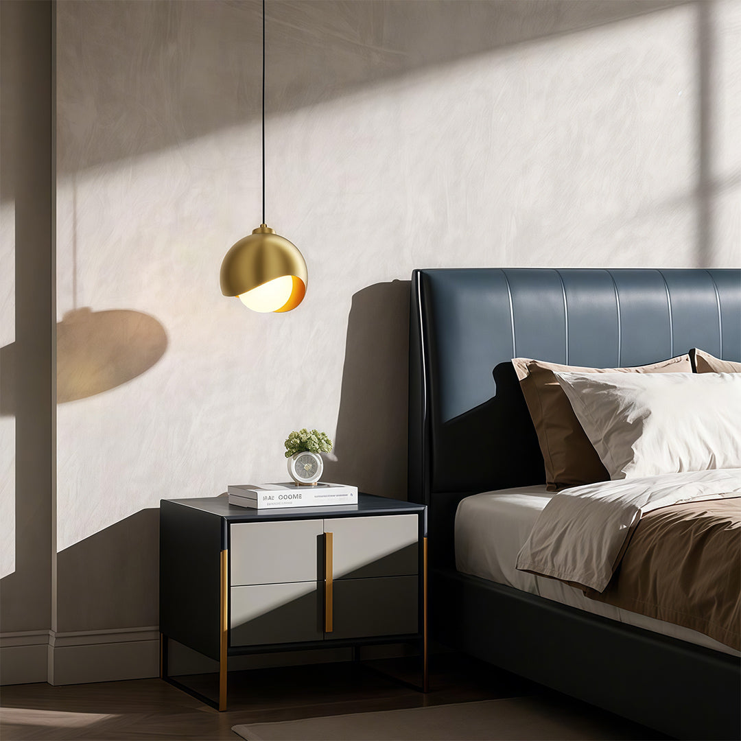 Glass pendant light fixture illuminating contemporary bedroom with grey upholstered headboard