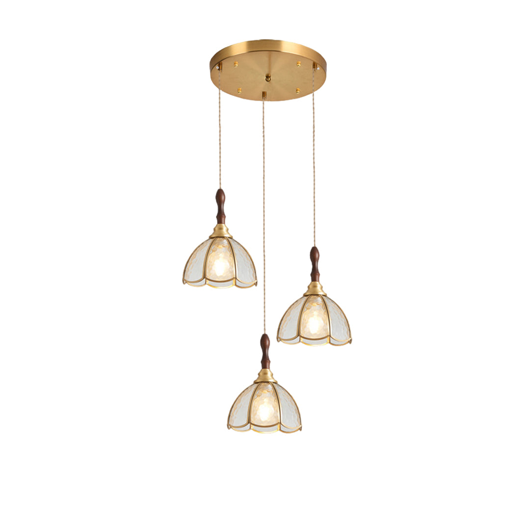 Close-up of a glass pendant light with a gold frame, highlighting the textured floral glass shade.