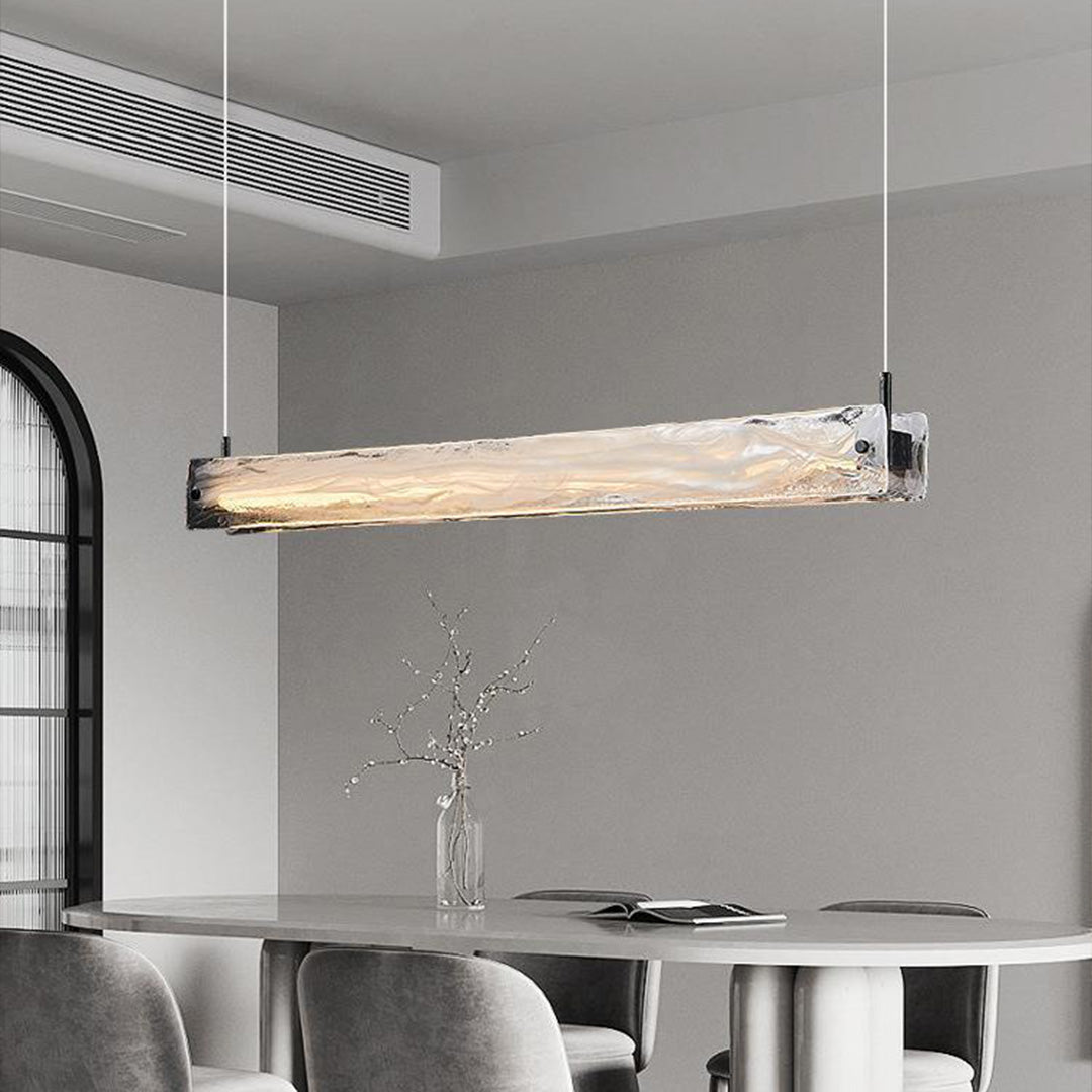 Modern glass pendant light for kitchen installed above minimalist dining area with concrete walls