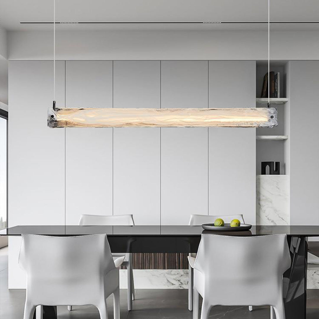 Contemporary glass pendant light for kitchen providing task lighting over sleek white kitchen island