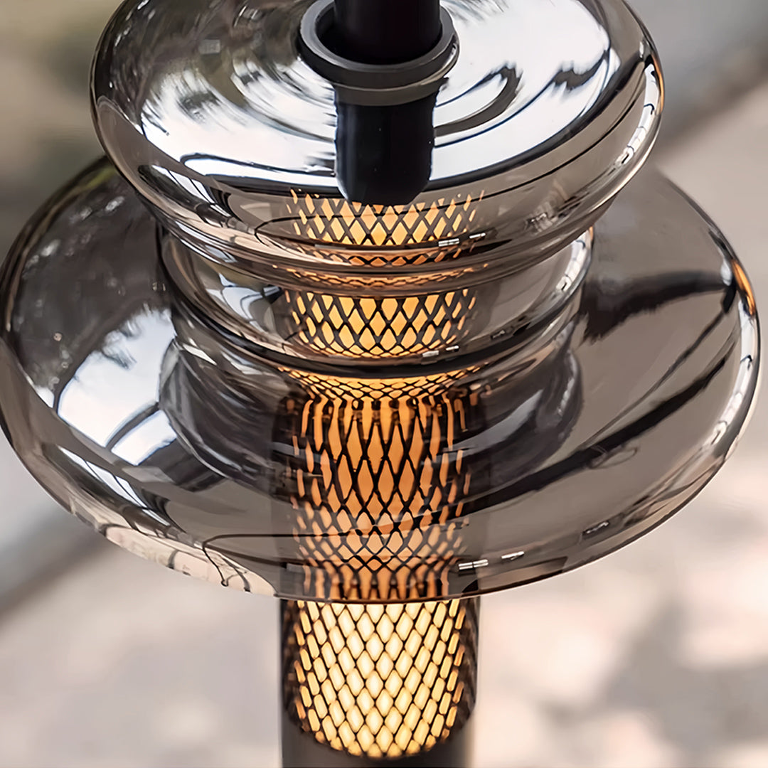Detailed view of glass pendant lights featuring chrome circular tiers and bronze mesh column