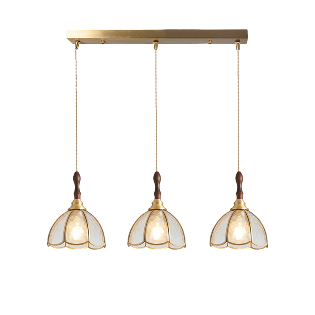 Three glass pendant lights with gold frames, hanging above a dining table in a stylish interior.