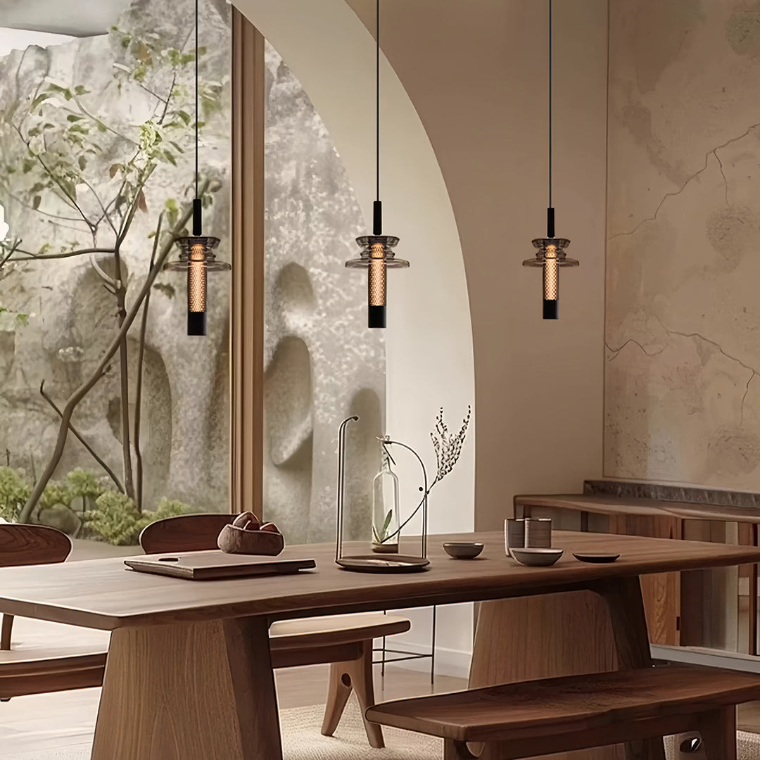 Multiple glass pendant lights displayed on rustic dining table with candles and earth-tone decor