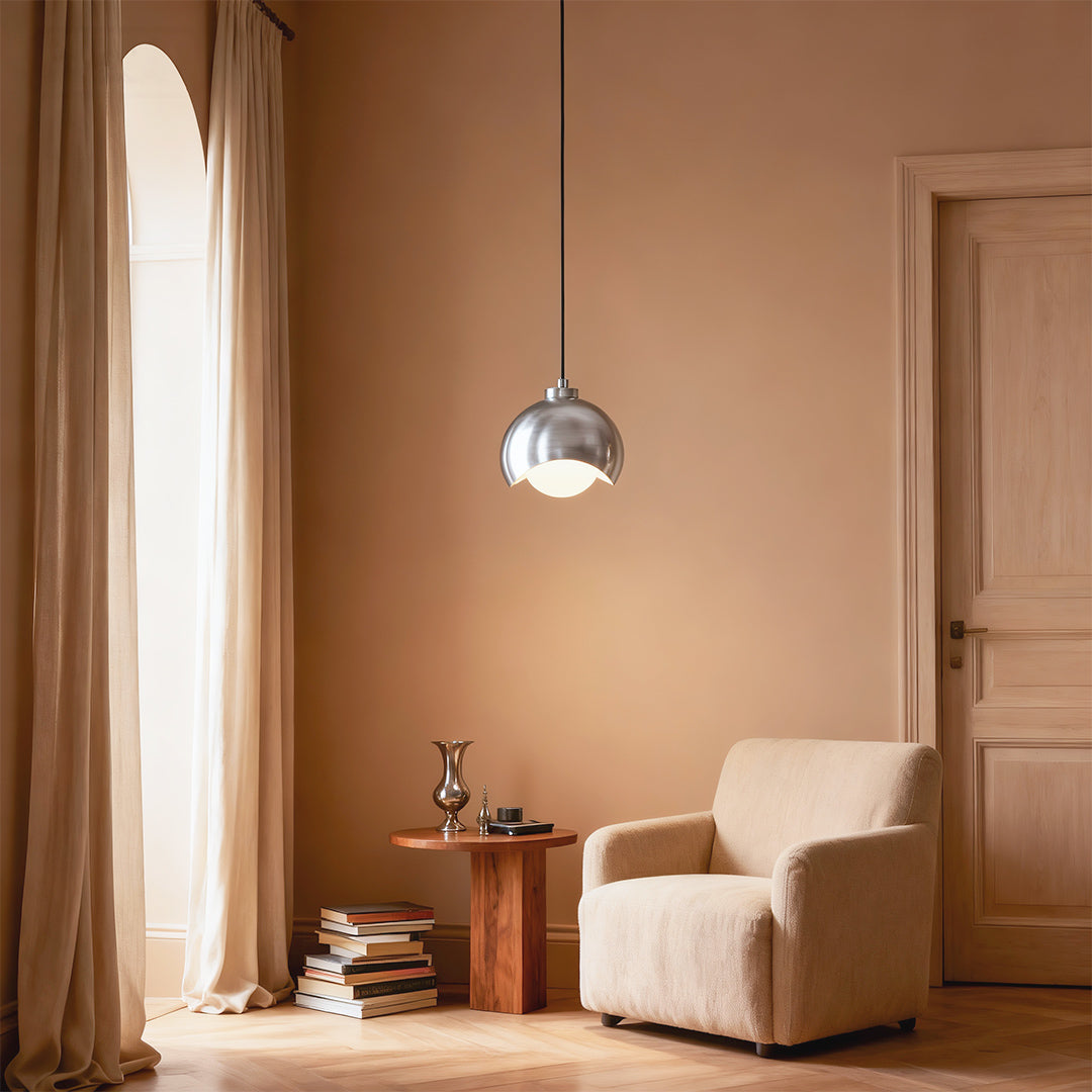 Glass pendant light fixture providing soft lighting in cozy reading nook with curtains