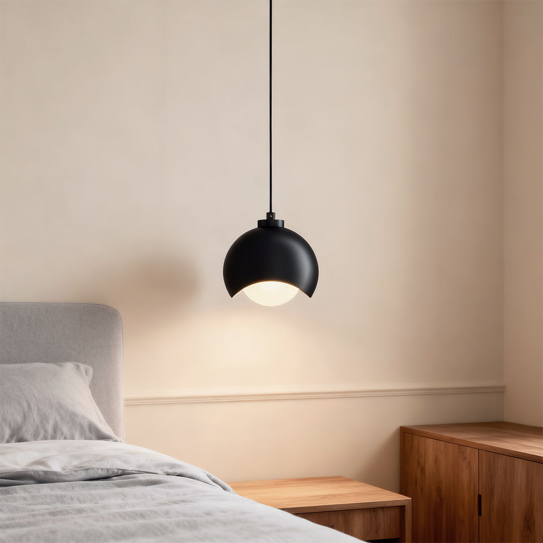 Glass pendant light fixture creating warm ambiance in minimalist bedroom with wooden furniture
