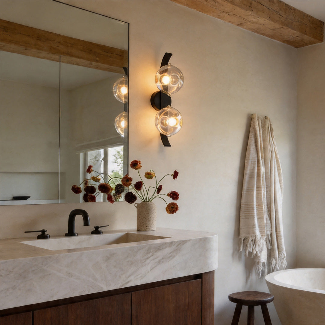 Modern glass wall sconces mounted beside bathroom mirror vanity.