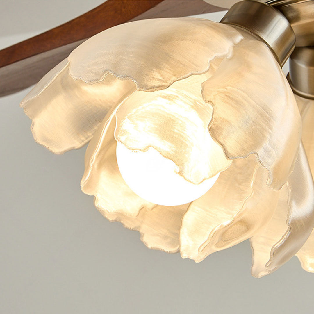 Close-up of ceiling fan with LED lighting showing a flower-shaped glass shade and warm illumination.