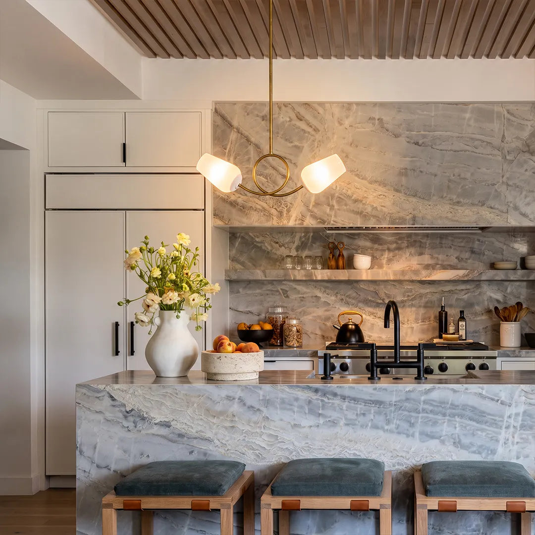 Glass vintage chandelier hanging above a marble kitchen island in a bright modern kitchen.