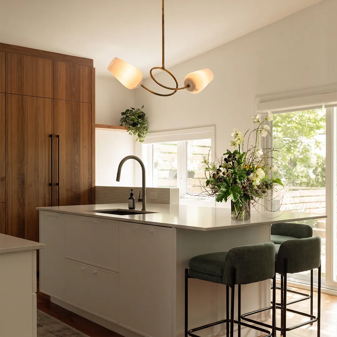 Glass vintage chandelier lighting a kitchen island in a bright open-plan interior.