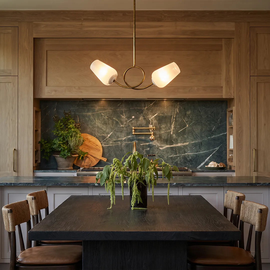 Glass vintage chandelier suspended over a dark dining table in a warm wood-paneled kitchen.