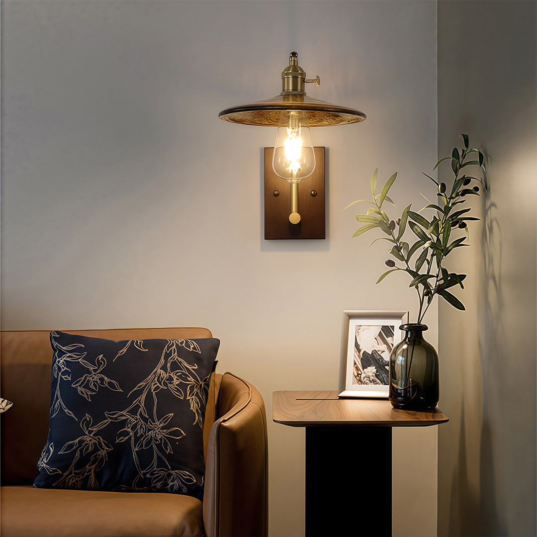  fixture with a spun metal shade, mounted on a wood square above a brown leather sofa and side table.