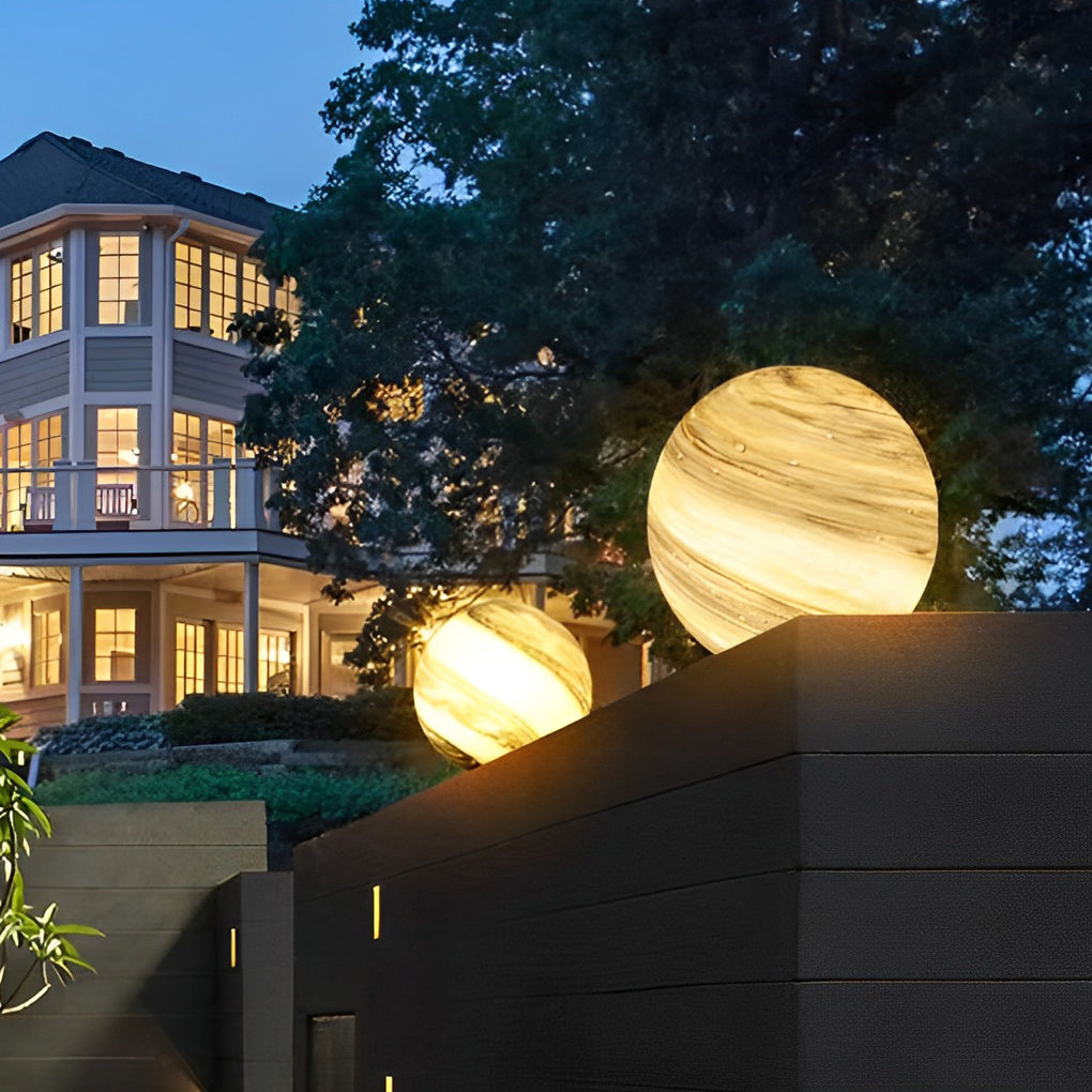Globe pillar lights illuminating garden area with soft light at night.