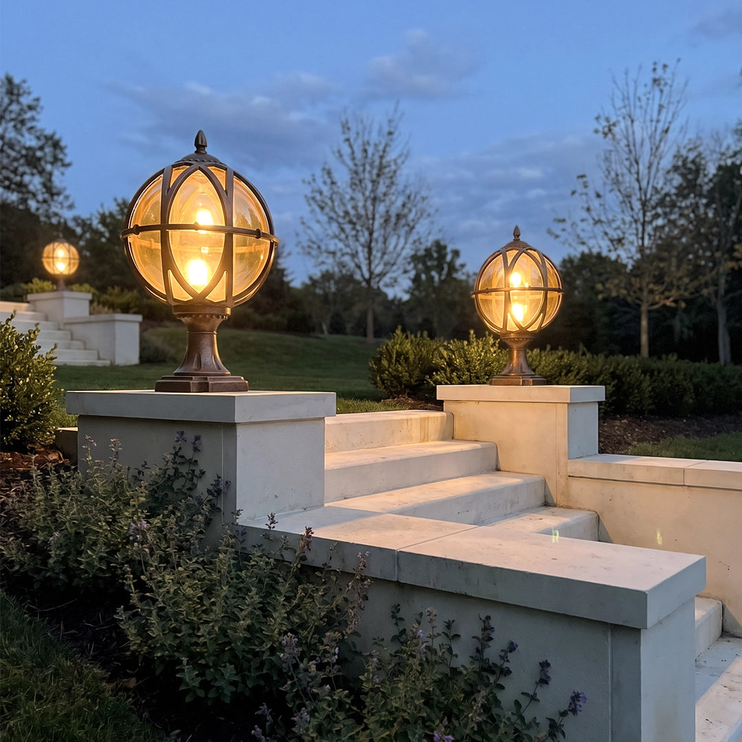 Globe pillar lights illuminating outdoor steps and stone columns in a landscaped yard at dusk.