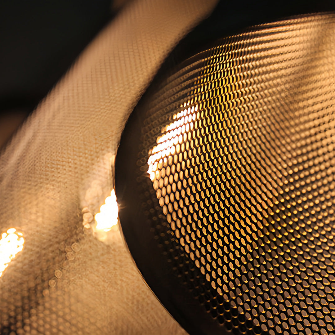Focus on the glowing light source visible through the curved perforated shade of the retro industrial pendant lights.