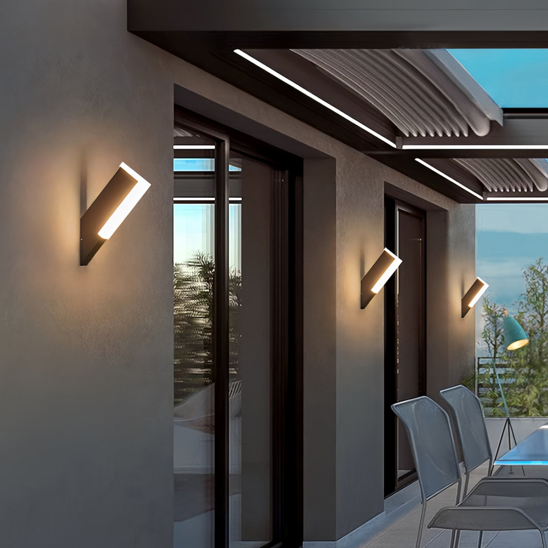 Warm glowing outdoor wall lantern light fixtures mounted on modern exterior patio walls.