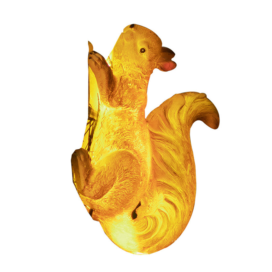 Glowing yellow squirrel solar light on white background showing illuminated LED features