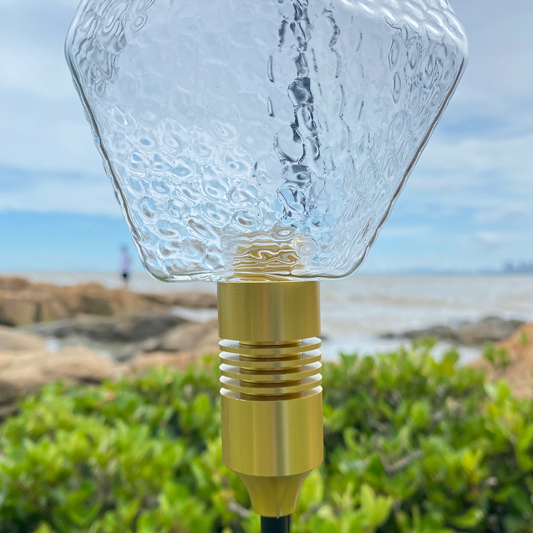 Close-up of gold base and textured globe sphere, designed as an elegant landscape lighting pathway detail.
