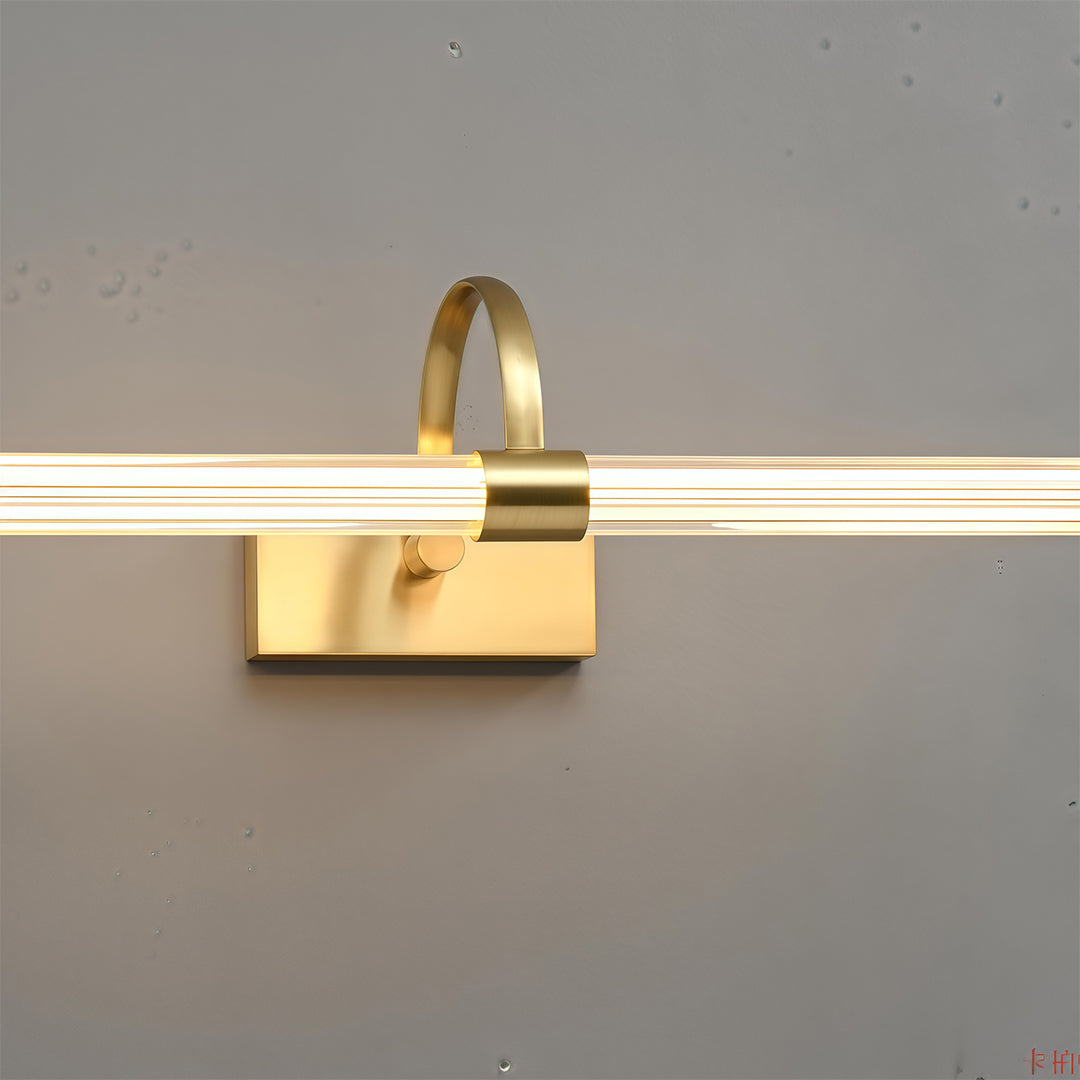 Gold bathroom vanity wall light positioned horizontally on grey surface demonstrating installation orientation.