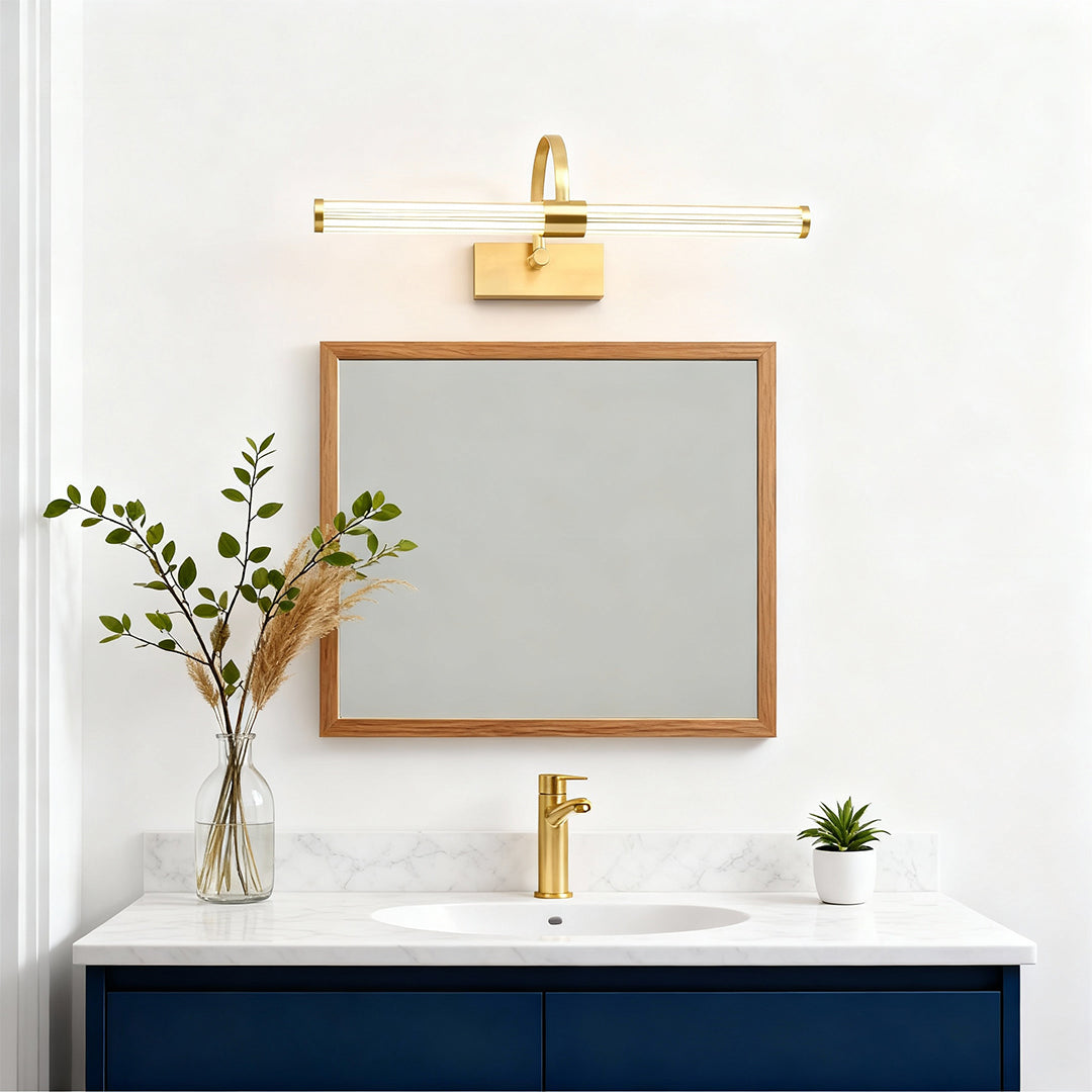 Gold bathroom vanity wall light above navy blue vanity with white countertop and gold-framed mirror.
