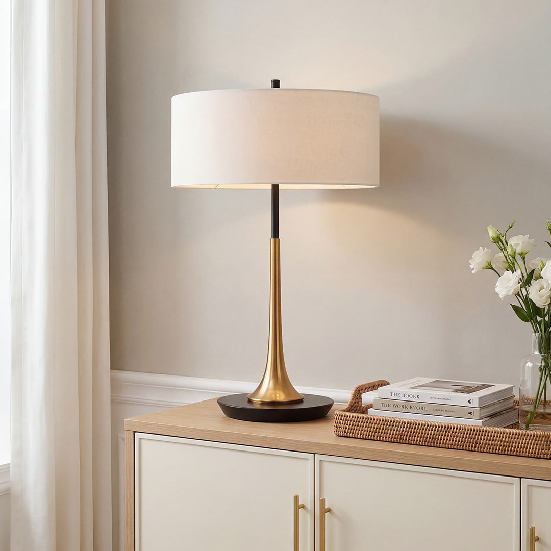 Elegant gold and black fabric table lamp with a linen shade on a white living room console unit.