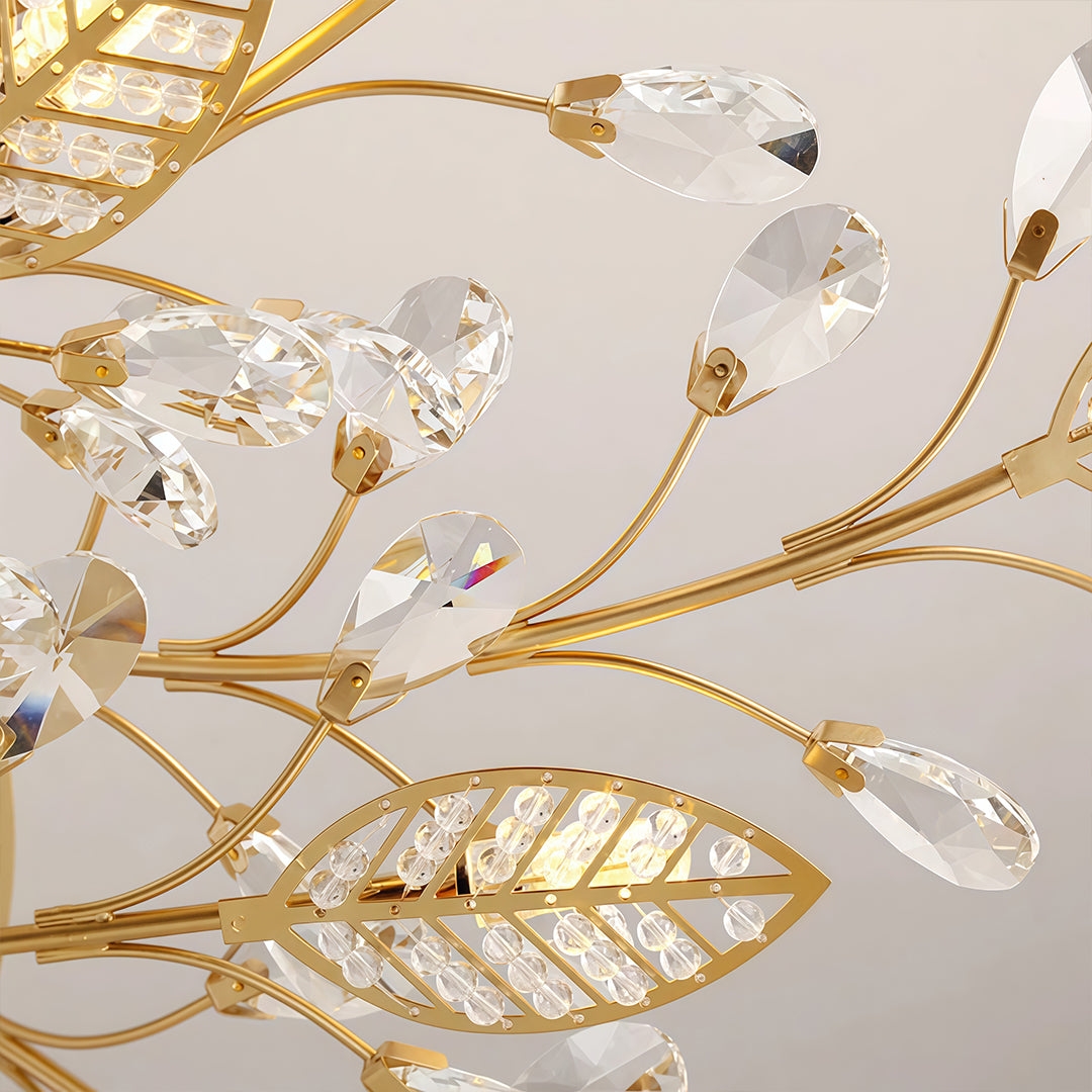 Close-up of a gold branch chandelier modern fixture showing leaf-shaped crystal elements and curved branch arms.
