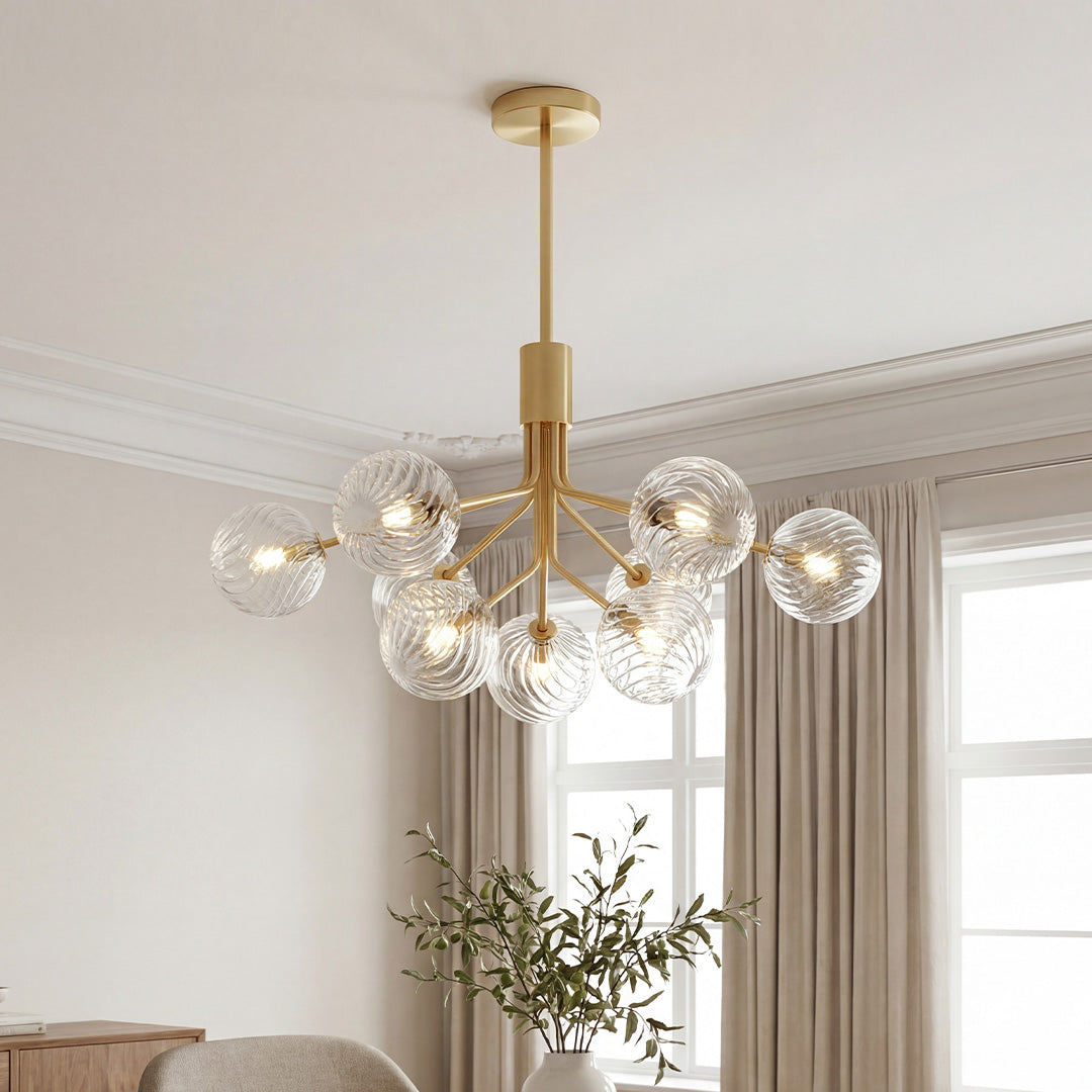 Stunning gold branching luxury modern chandeliers featuring ribbed clear glass globes in an elegant bright living room.