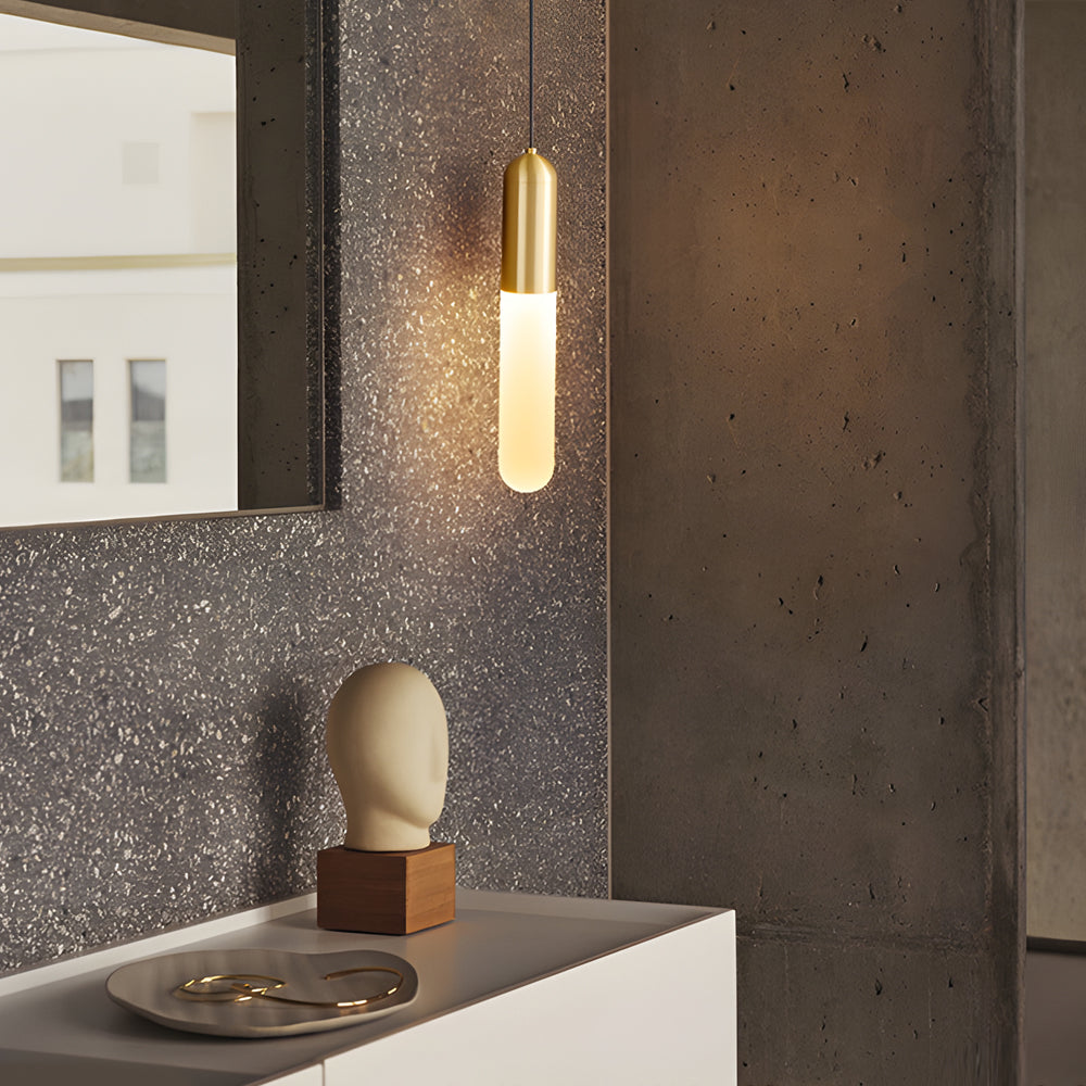 Elegant Gold Capsule Pendant Light glowing against a textured accent wall in a modern entryway.