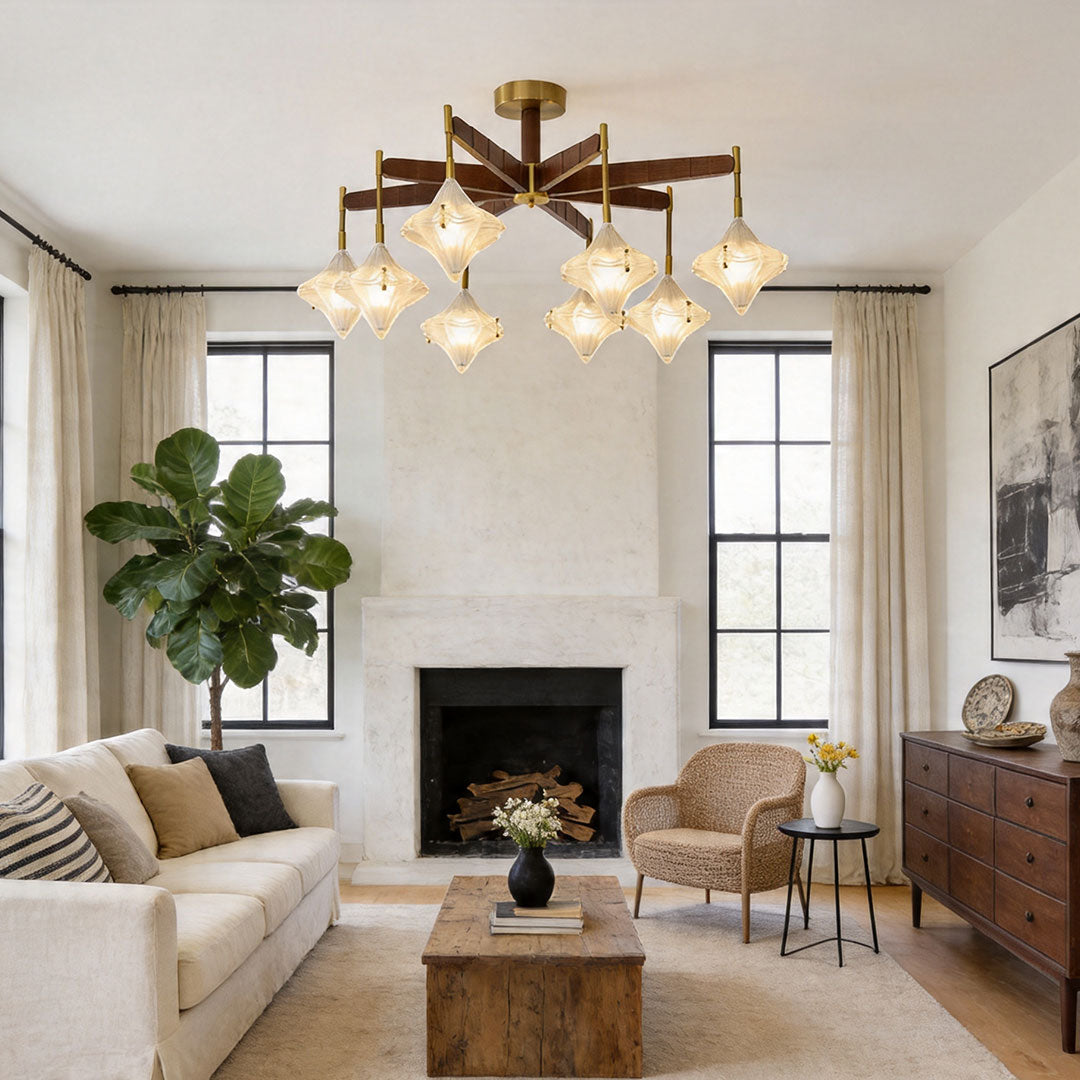 Elegant gold chandelier with multiple glass pendants in a warm living room with fireplace and plants.