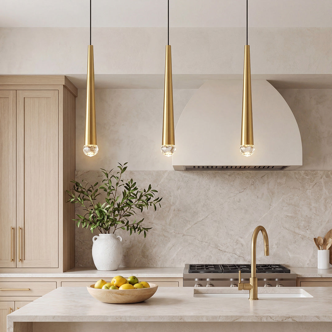 Trio of elegant gold cone pendant lights with crystal tips over a luxury marble kitchen island.