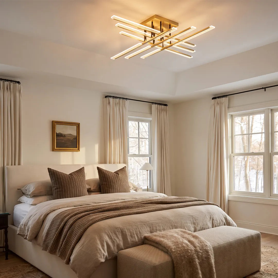 Gold cross ceiling light mounted above a bedroom, featuring a modern crystal-accented design with intersecting linear arms and warm illumination.