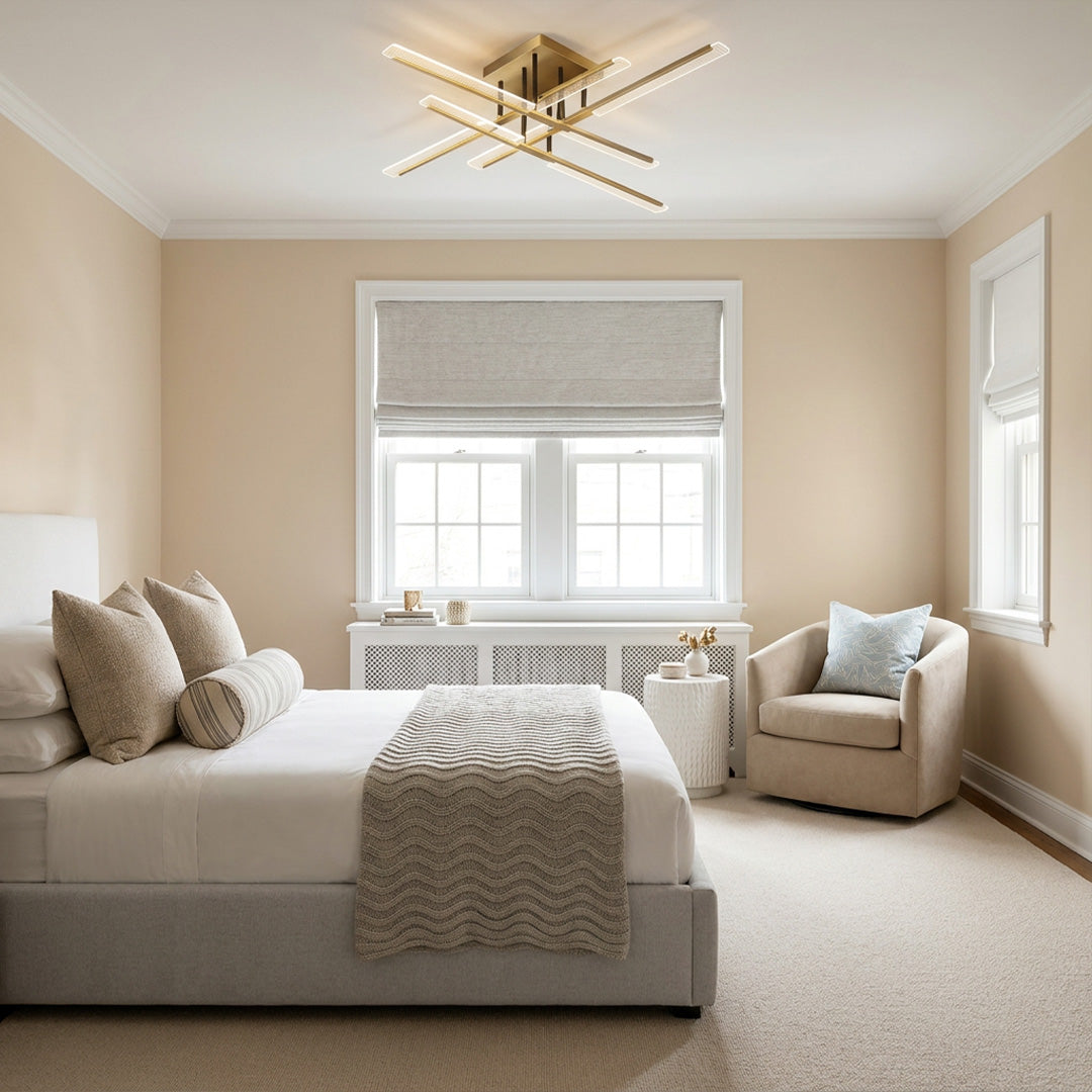 Gold cross ceiling light installed in a bright bedroom, adding a modern geometric focal point above the bed and window seat.