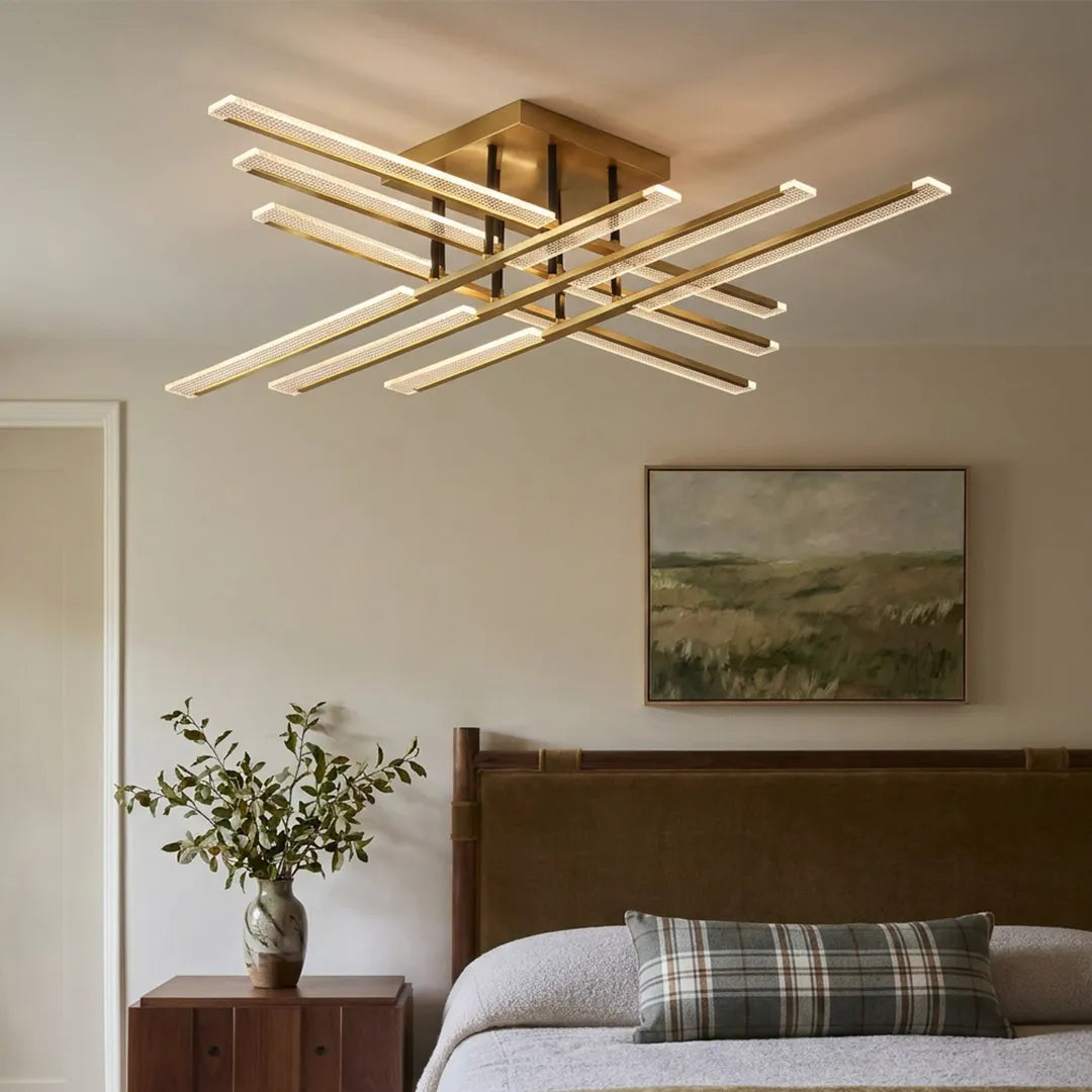 Gold cross ceiling light mounted in a cozy bedroom, showcasing a contemporary crossed-bar design with warm illumination above the bed.