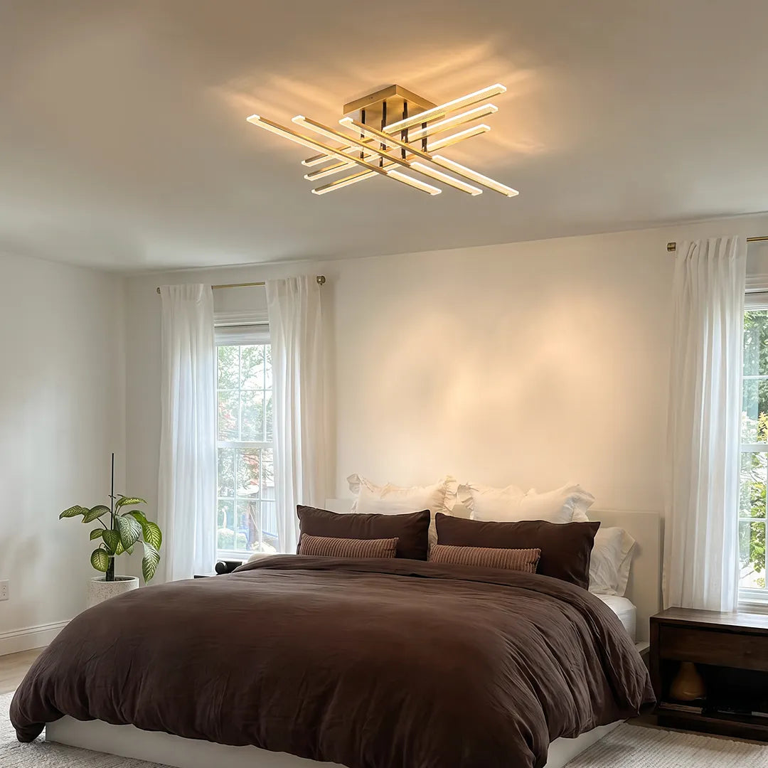 Gold cross ceiling light installed in a modern bedroom, showcasing a geometric flush mount design with sparkling crystal bars and soft warm light.
