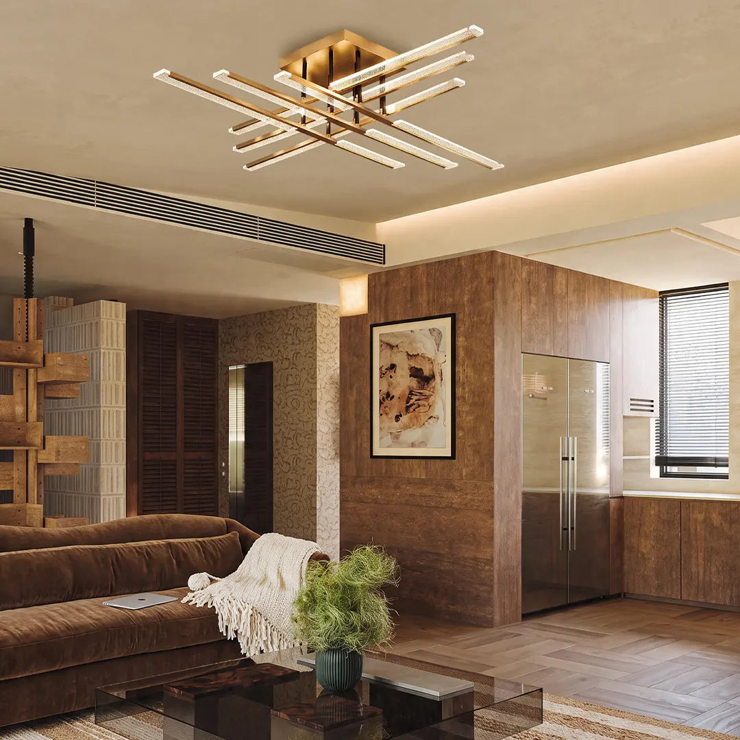 Gold cross ceiling light installed in a modern interior with wood accents, sofa seating, and kitchen views.