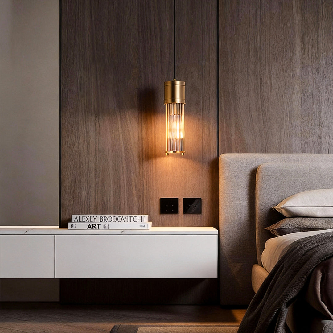 Gold cylinder pendant light used as bedside lighting in modern bedroom.